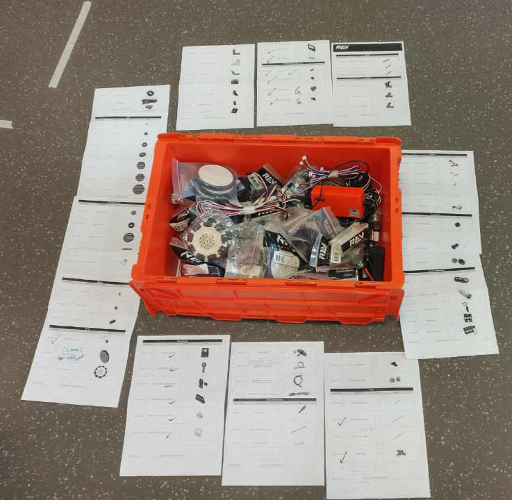 A set of check lists for REV parts laid out around an open box of parts